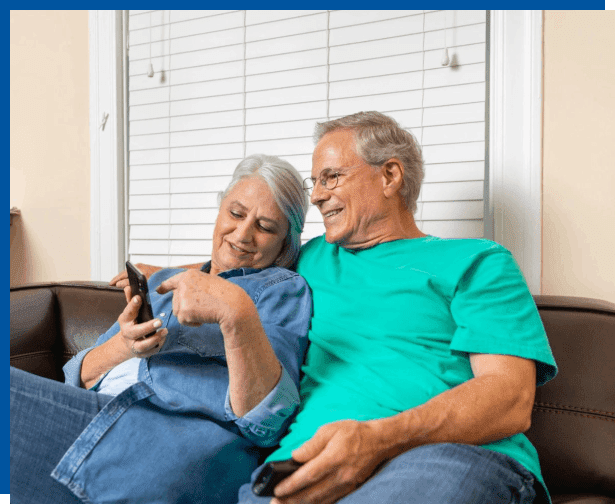 A man and woman sitting on the couch holding remotes.