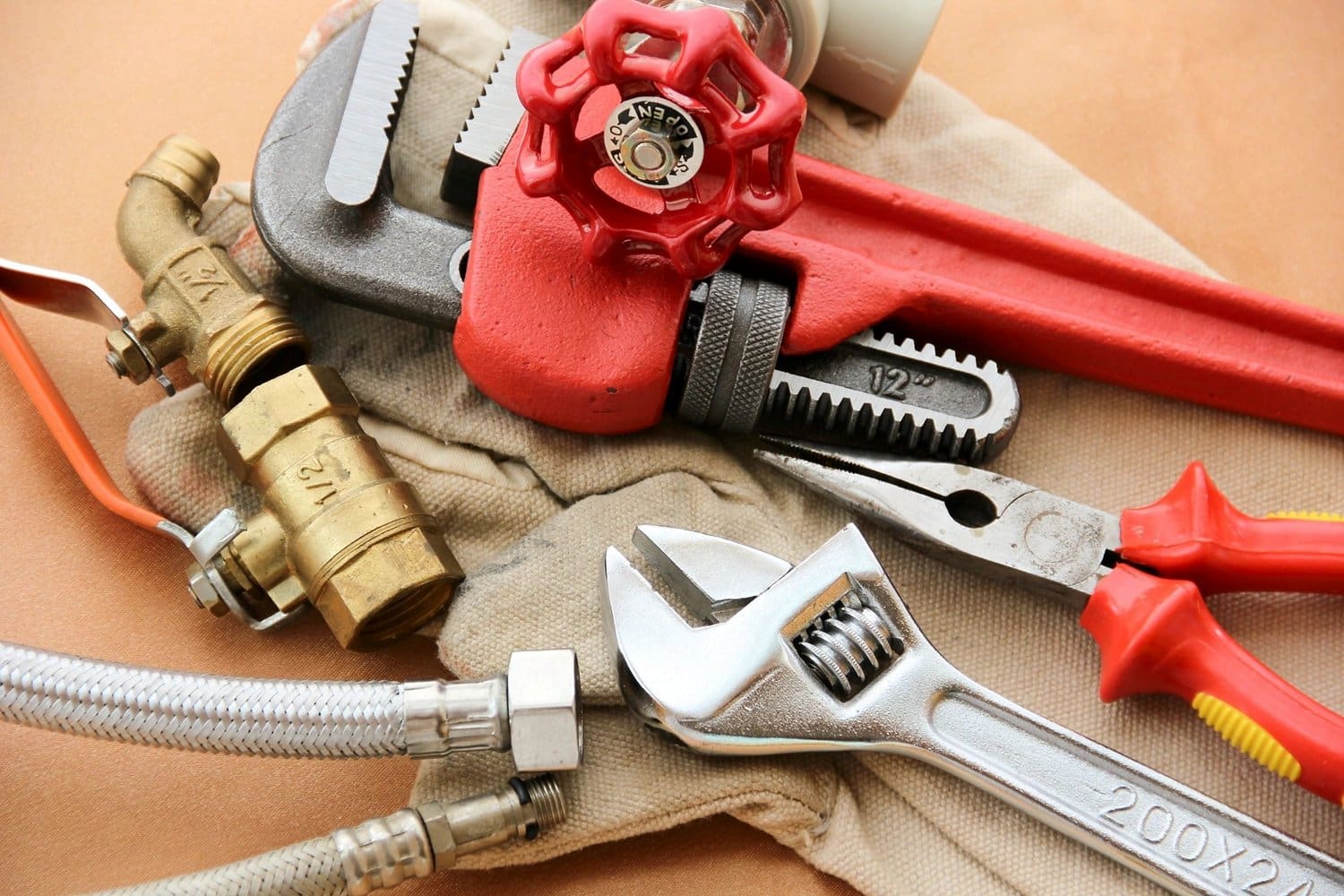 A pair of wrenches and some pipes on top of a table.