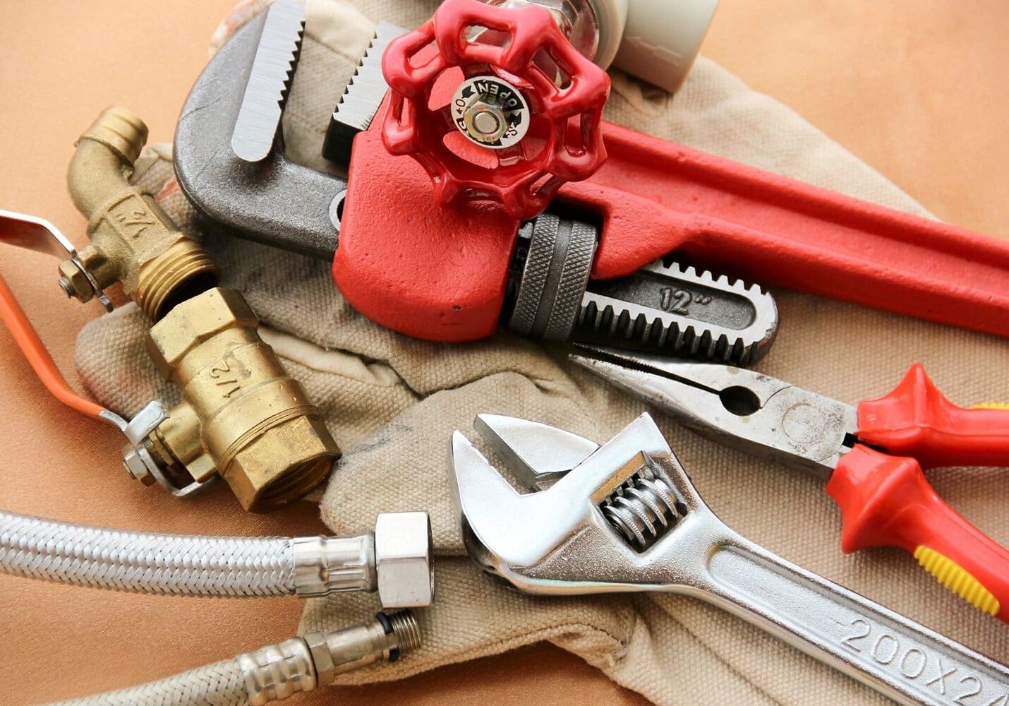 A pair of wrenches and some pipes on top of a table.